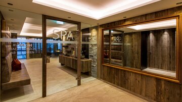 A modern spa with wooden paneling and soft lighting. The reception area is inviting and stylishly designed.