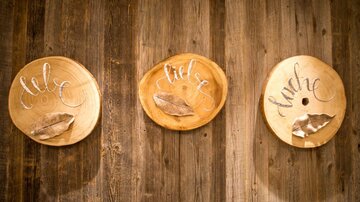 Three round wooden plates hang on a wall. Each plate has a word in cursive script: "Love", "Desire", and "Hunger".
