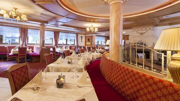 An elegant restaurant with a cozy atmosphere.  
The tables are beautifully set and the decor is stylish with red and gold accents.