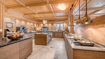 A modern kitchen with wooden paneling and elegant pendant lights. The open work surfaces provide ample space for meal preparation.