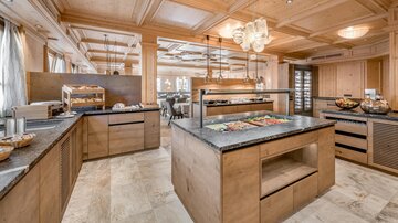 A modern restaurant with wood paneling and elegant lighting. The buffets are tastefully arranged and offer a variety of dishes.