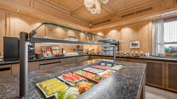 An elegant breakfast area with fresh fruits and a modern buffet arrangement. The warm wooden paneling creates an inviting atmosphere.