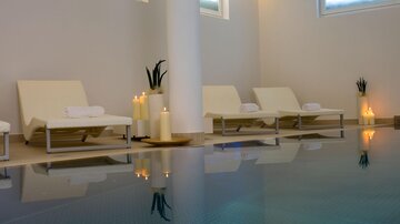 An elegant wellness area with loungers and soft lighting. The tranquil pool reflects the relaxing atmosphere. | © Rössle