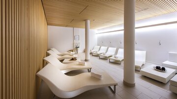 A modern wellness area with elegant loungers and soft lighting. The walls are made of light wood, and the room exudes tranquility. | © Rössle