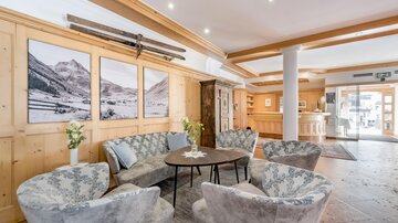 An elegant lounge area with comfortable armchairs and a round table. Pictures of mountains hang on the walls, and the atmosphere is inviting. | © Rössle