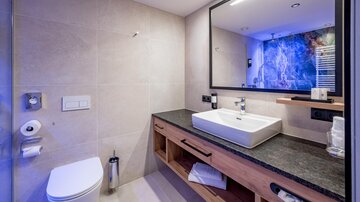 A modern bathroom with a large mirror and an elegant sink. The walls are in neutral colors, and there are wooden details.