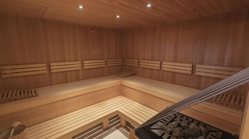 A modern sauna with a wooden bench and soft lighting. The room is inviting and provides a place of relaxation.