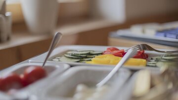 A set table with fresh vegetables. On the plate, cucumbers, bell peppers, and tomatoes are beautifully arranged.