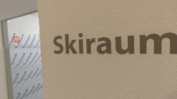 A sign reading "Ski Room" on a wall. In the background, coat hooks are visible.