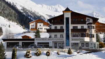 A charming hotel in a snow-covered mountain landscape. Surrounded by snowy hills and trees, it offers an idyllic atmosphere.