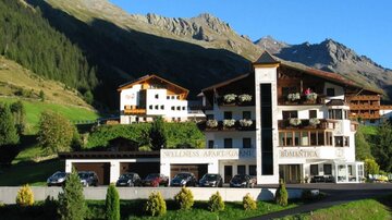A picturesque hotel in the mountains with a beautiful landscape. The property is surrounded by green meadows and majestic mountain slopes.