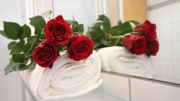 A beautiful sight with red roses on a freshly folded towel. The bathroom is reflected in the background.