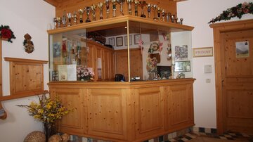 A reception area with wooden decor and numerous trophies on the wall. The furnishings are cozy and inviting.