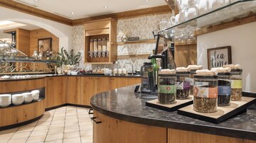 A cozy tea room with wooden shelves and a selection of tea glasses. The decor is warm and inviting, with well-kept surfaces and decorative elements.