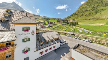 A charming building with the inscription "Wilder Hof" in a picturesque mountain landscape. In the background, green meadows and gently rolling hills can be seen.