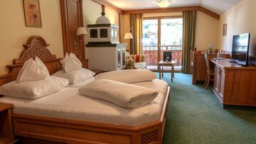 A cozy hotel room with two beds, beautiful wood paneling, and a balcony. The room is bright and cheerfully furnished.