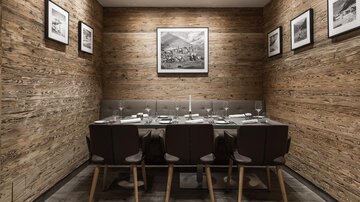 A stylish dining area with wooden paneling and a large table. Pictures hang on the walls, and the room feels cozy and inviting.