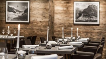 An elegant restaurant with wooden walls and atmospheric lighting. The tables are tastefully set and invite you to linger.