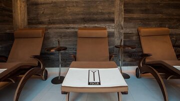 A relaxing rest room with elegant loungers and small side tables. The warm wooden accents create a cozy atmosphere.